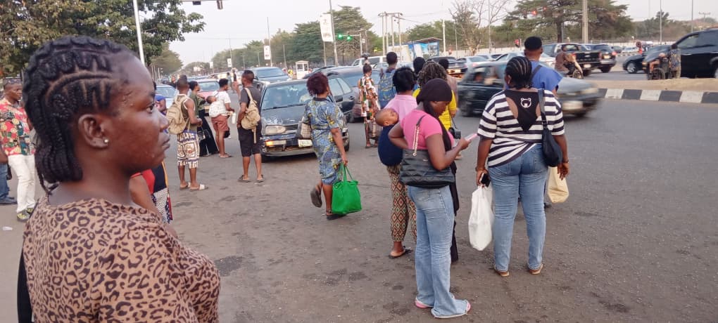 A street scene in Abuja, showing residents and vehicles.