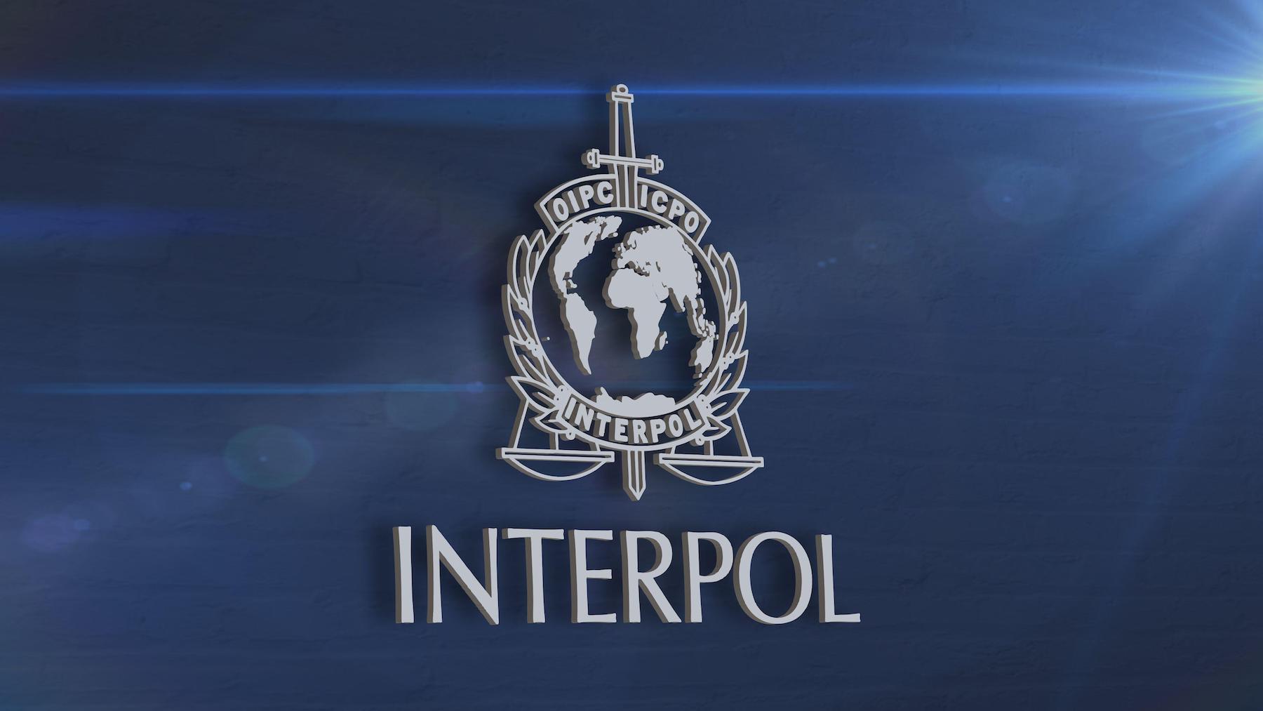 INTERPOL logo displayed on a screen during a press conference.
