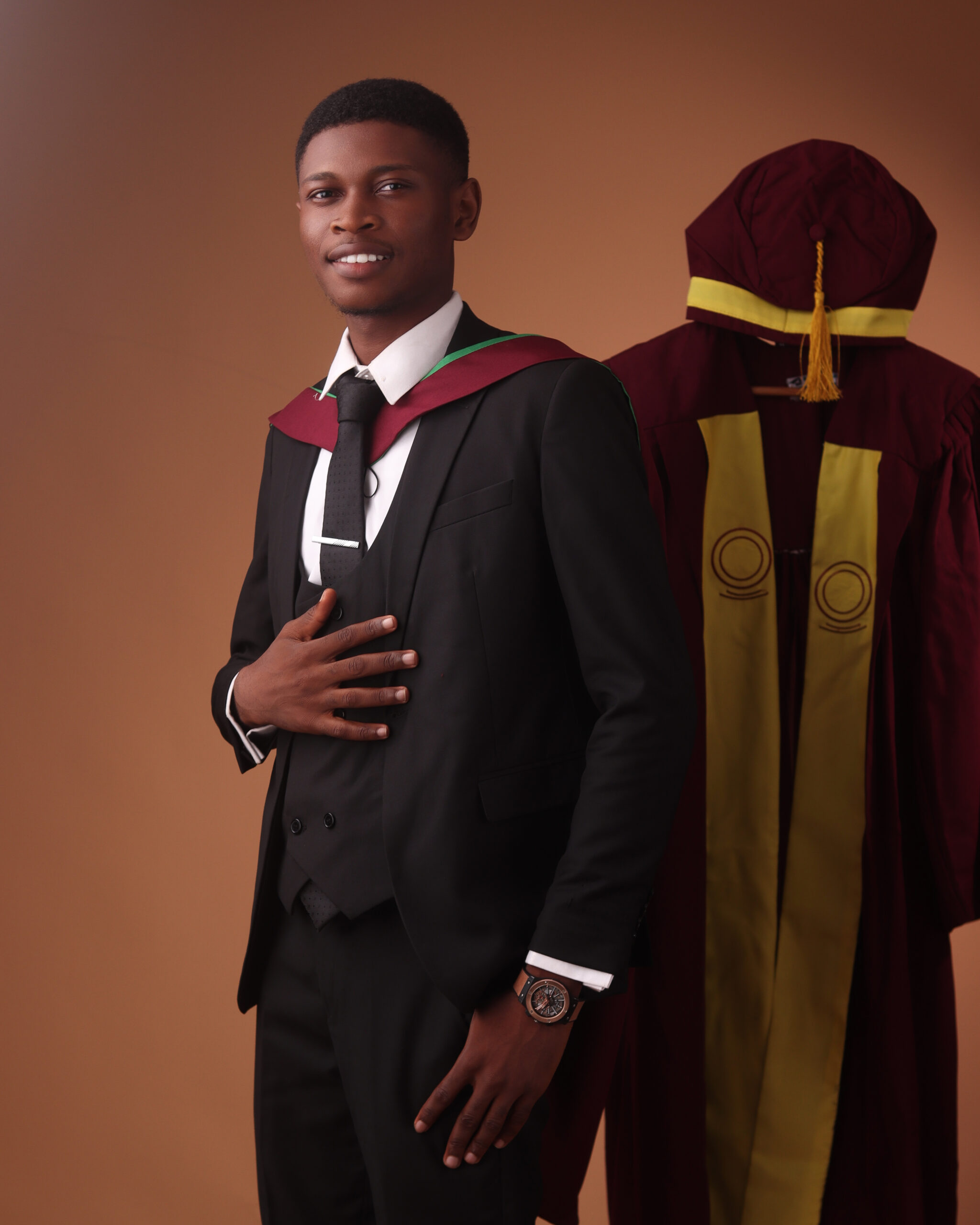 Benedict Umeozor smiling while holding his graduation certificate.