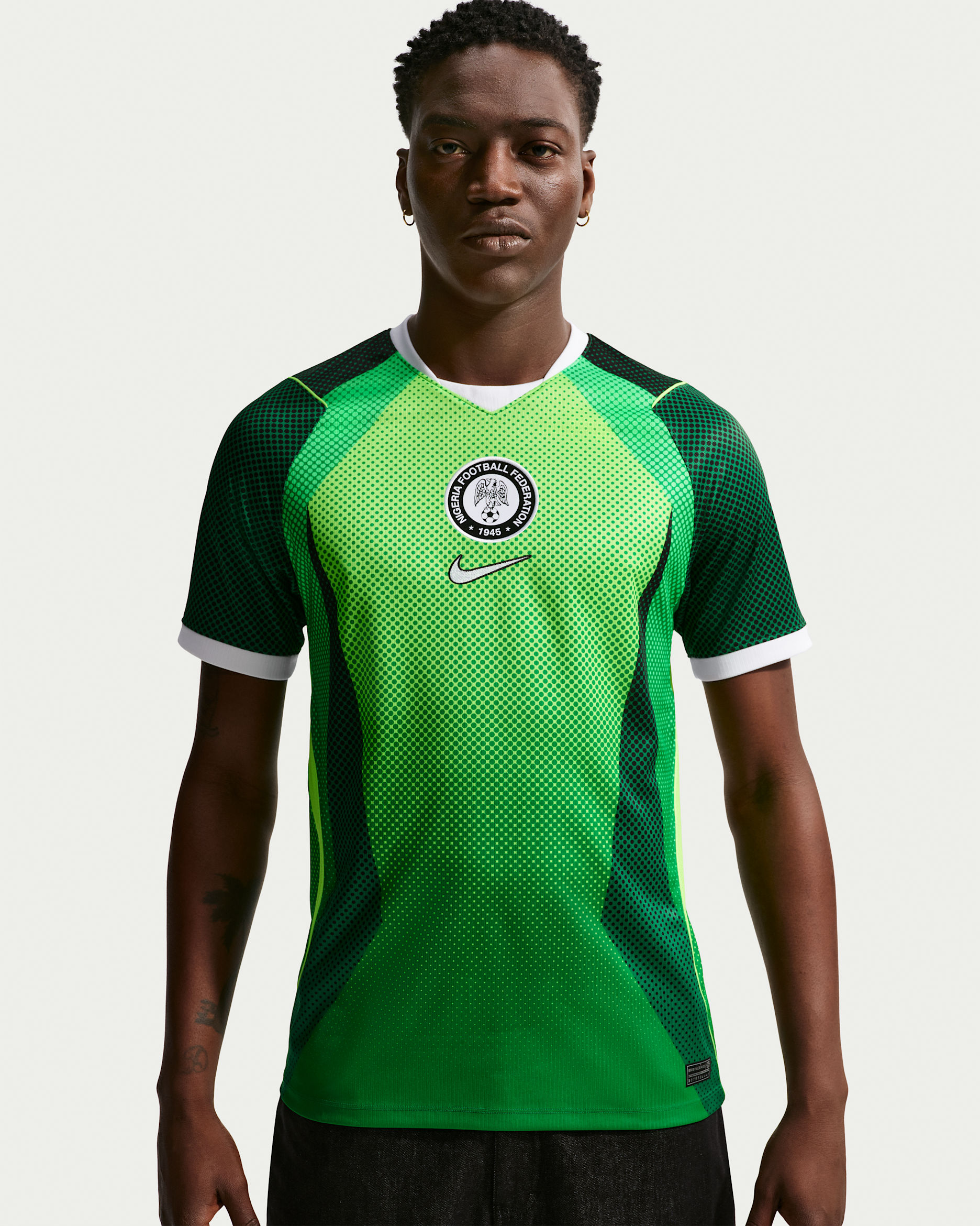 A male model showcasing the vibrant lemon green 2026 Nike Super Eagles home jersey with dark green armour-style side panels.