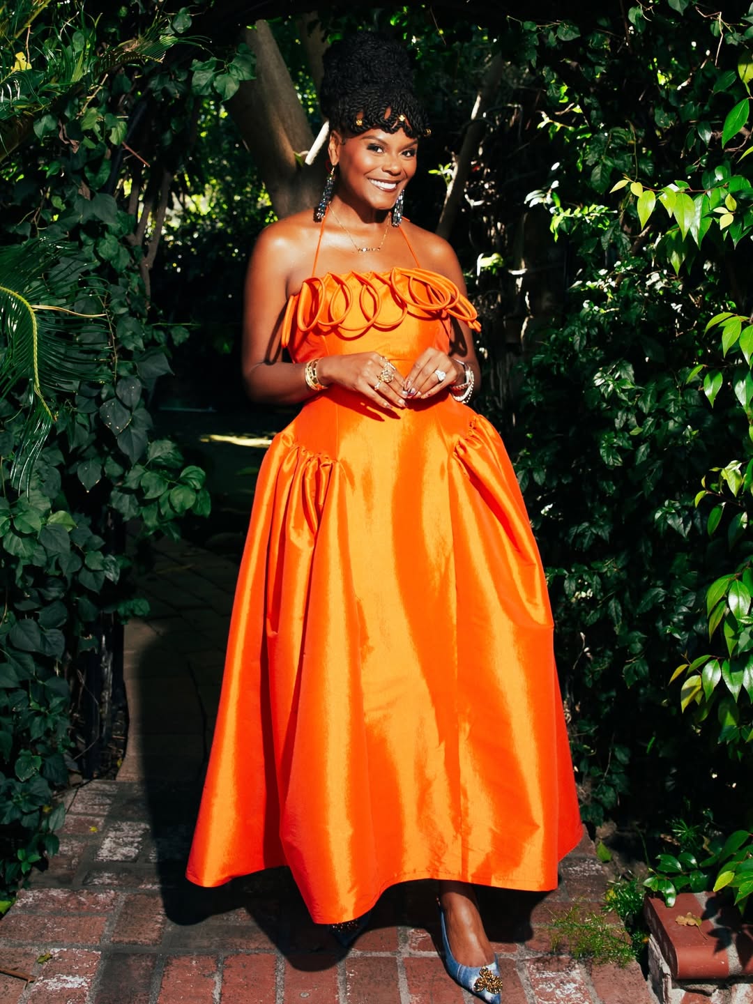 Actress Tabitha Brown at the 57th NAACP Image Awards, wearing a vibrant orange sculptural gown by Desirée Iyama.