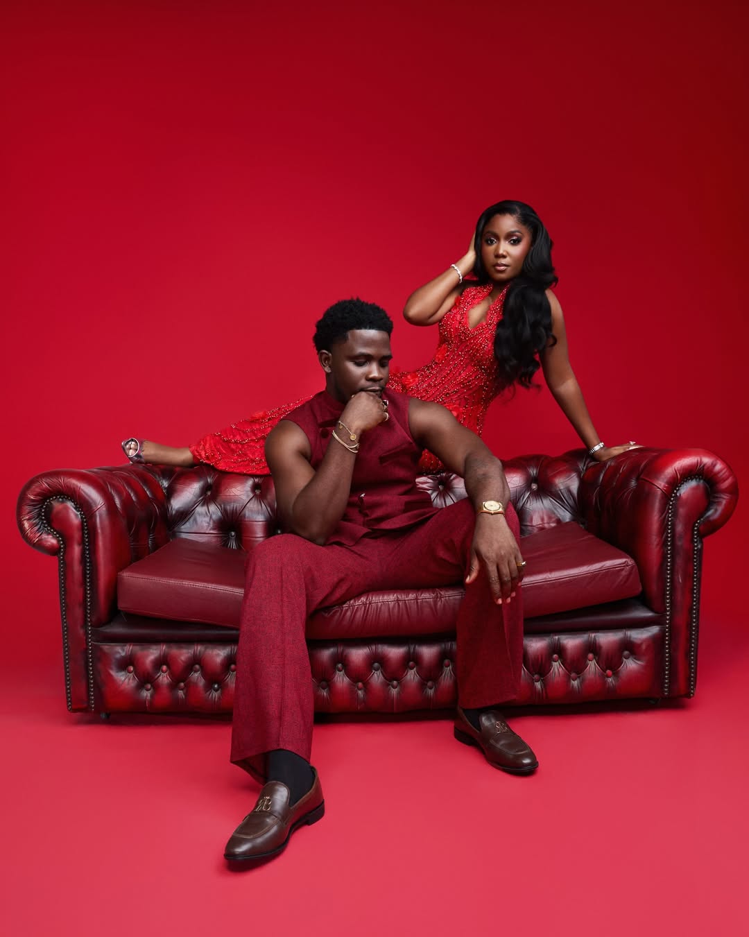 Femi Dapson in a deep burgundy suit and Simi Sanya in a crystal-beaded red gown posing for their pre-wedding photoshoot.