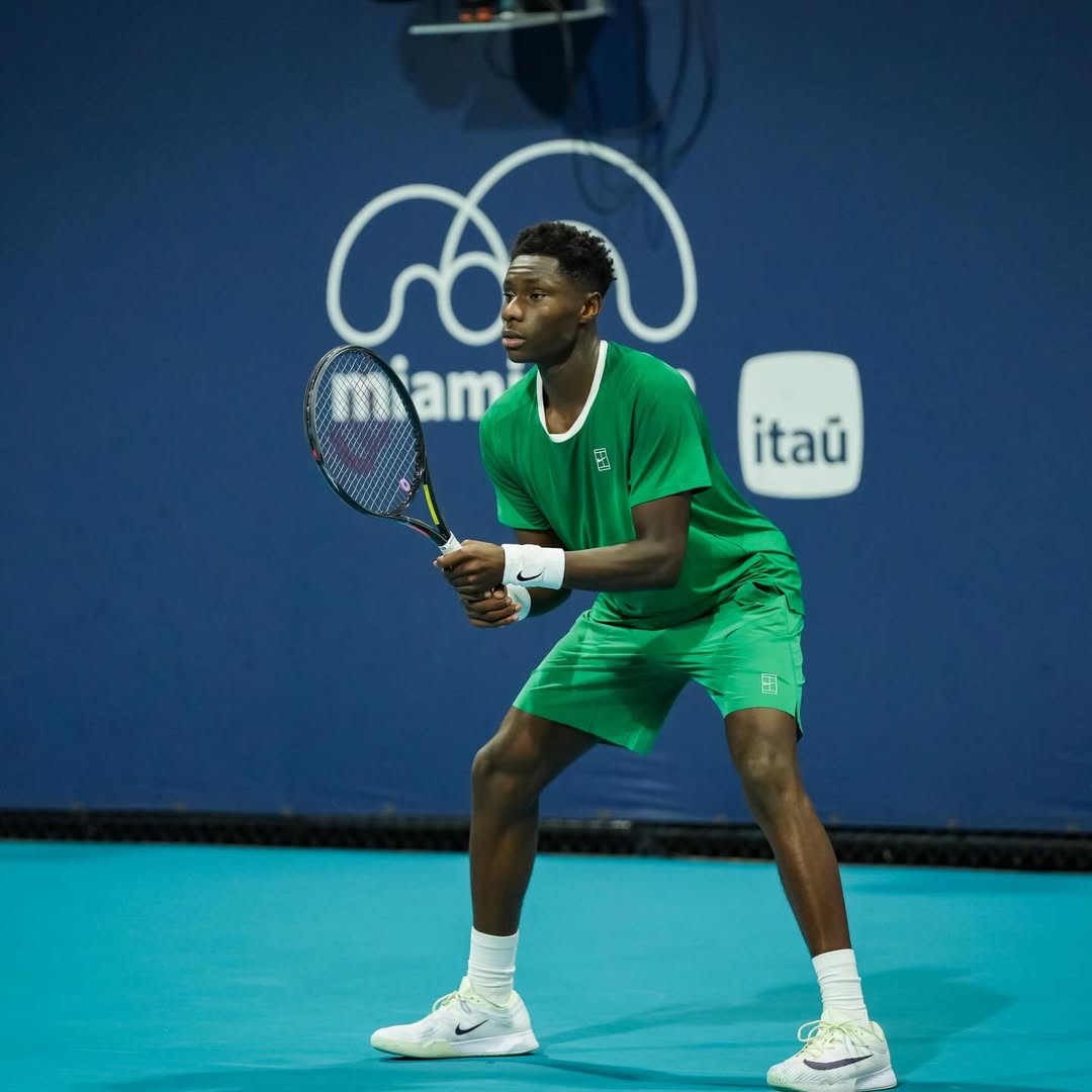 17-year-old French-Ivorian tennis player Moïse Kouame in a focused receiving stance on the teal hard courts of the 2026 Miami Open.
