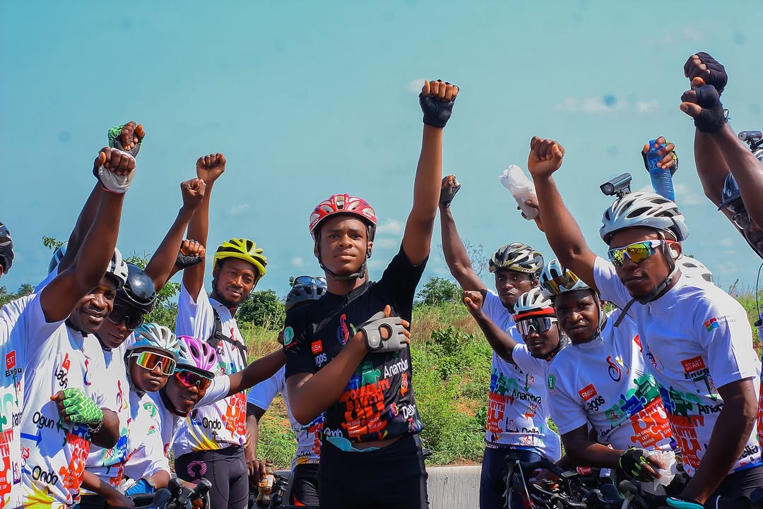 Kanyeyachukwu Tagbo-Okeke and a group of Nigerian cyclists raising their fists in a power salute for autism awareness.