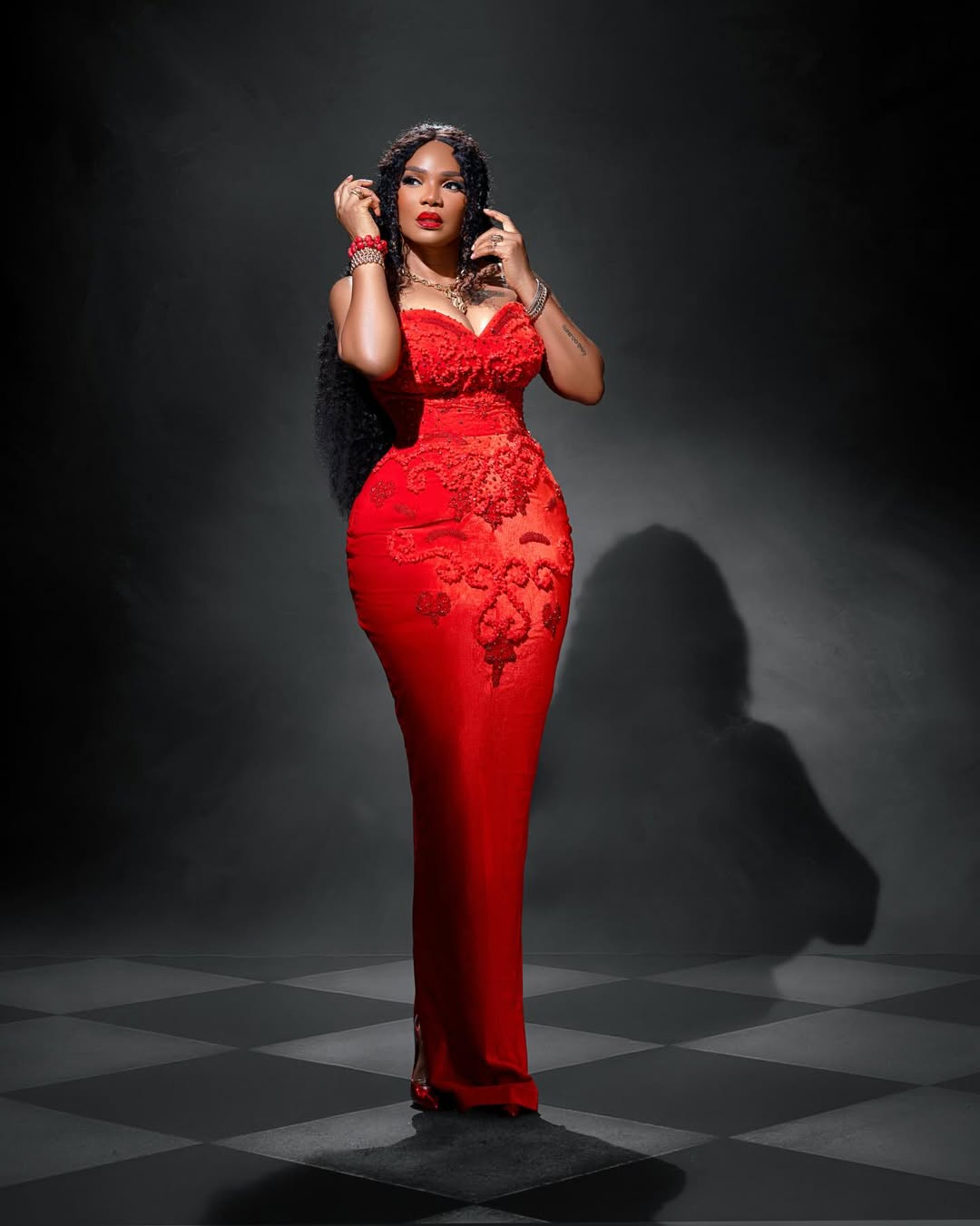 Actress Iyabo Ojo wearing a custom red Medlin Couture mermaid gown with intricate tonal floral appliqué for Senator Florence Ita Giwa's 80th birthday celebration.