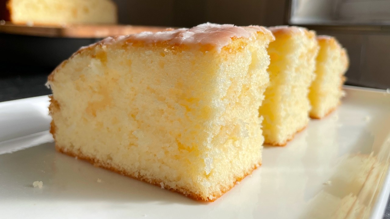 A close-up of a freshly baked soft vanilla cake with a glossy glaze.