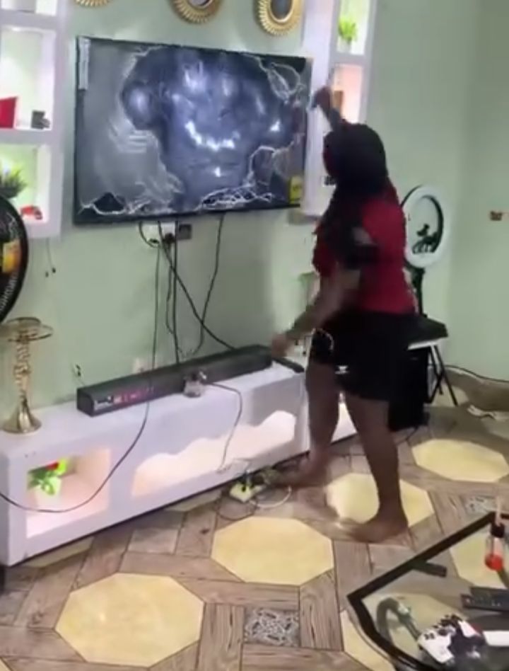 An angry girlfriend using a knife to vandalize her boyfriend's TV.